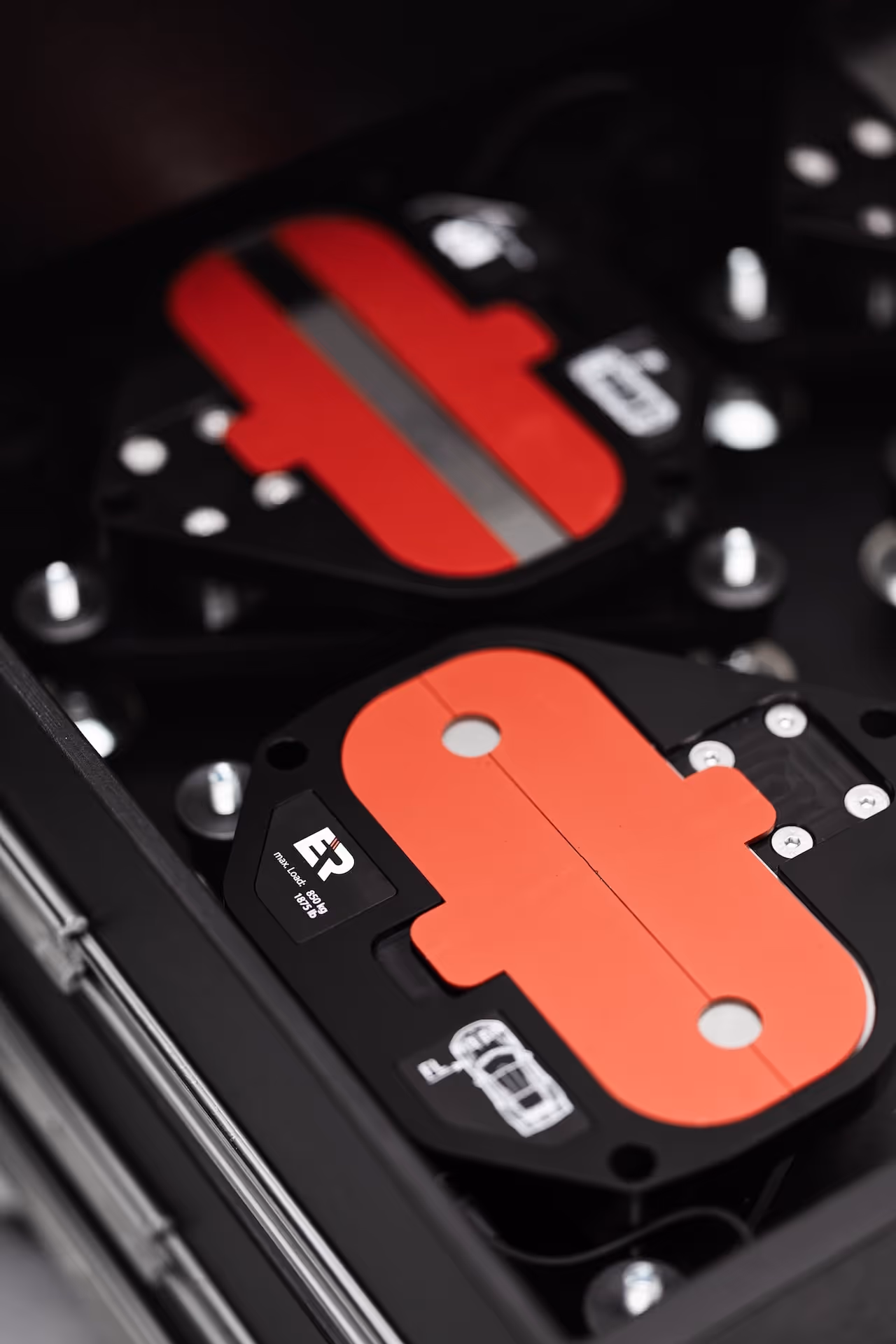 Close-up of a black and red mechanical component with metal screws and branding details inside a storage case.