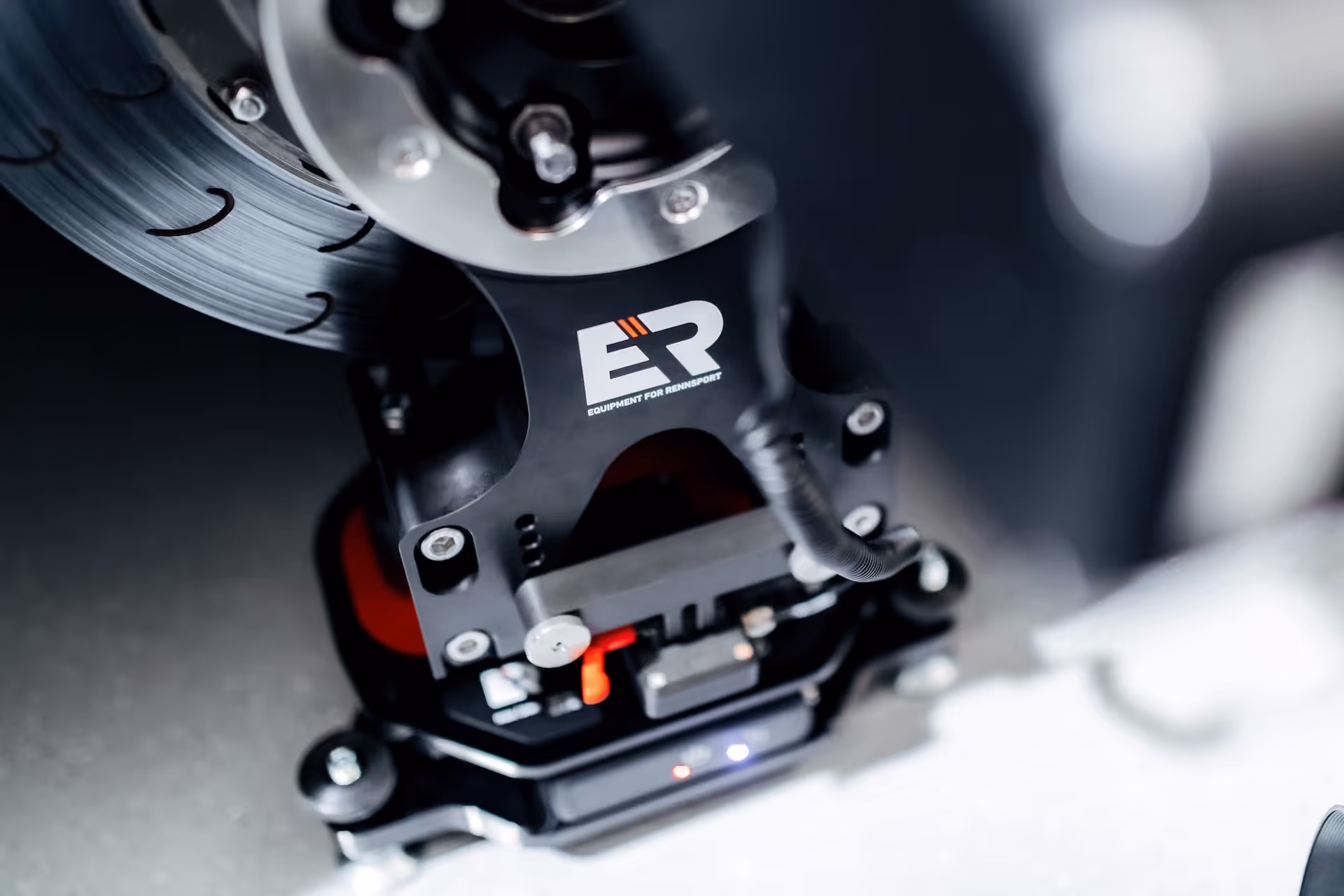 Close-up of a high-performance brake caliper with drilled brake disc and ER Racing logo.