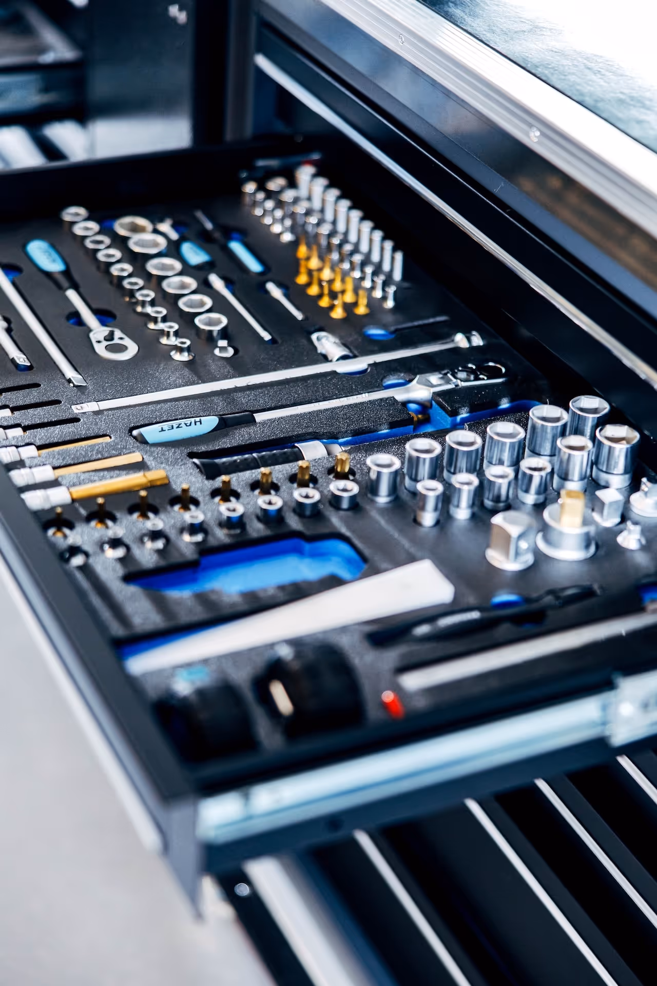 Open tool drawer with organized socket wrenches, screwdrivers, bits, and ratchets in a foam insert.