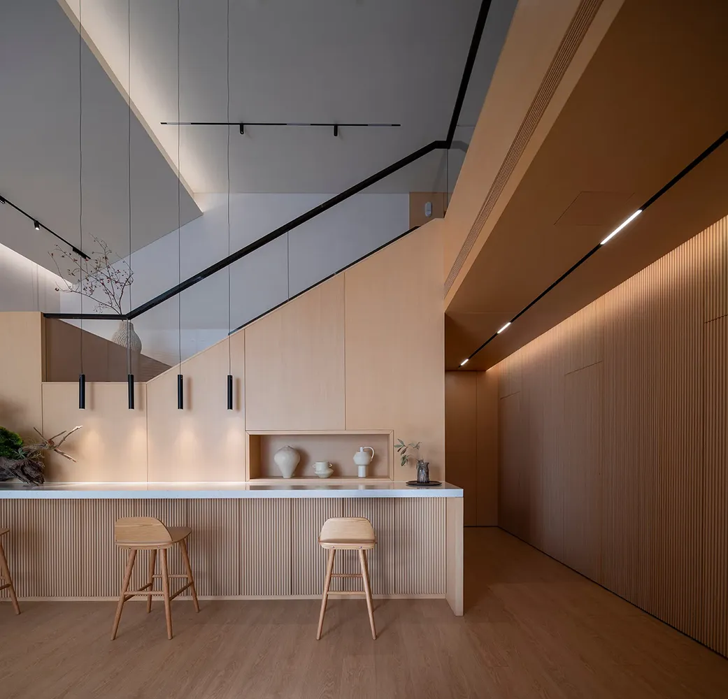 Moderner Küchenbereich mit hellen Holzstühlen, weißer Arbeitsplatte und minimalistischen Pendelleuchten.