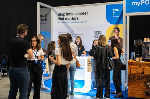 People gathered at a myPOS career booth with a sign reading ‘Step into a career that matters.’