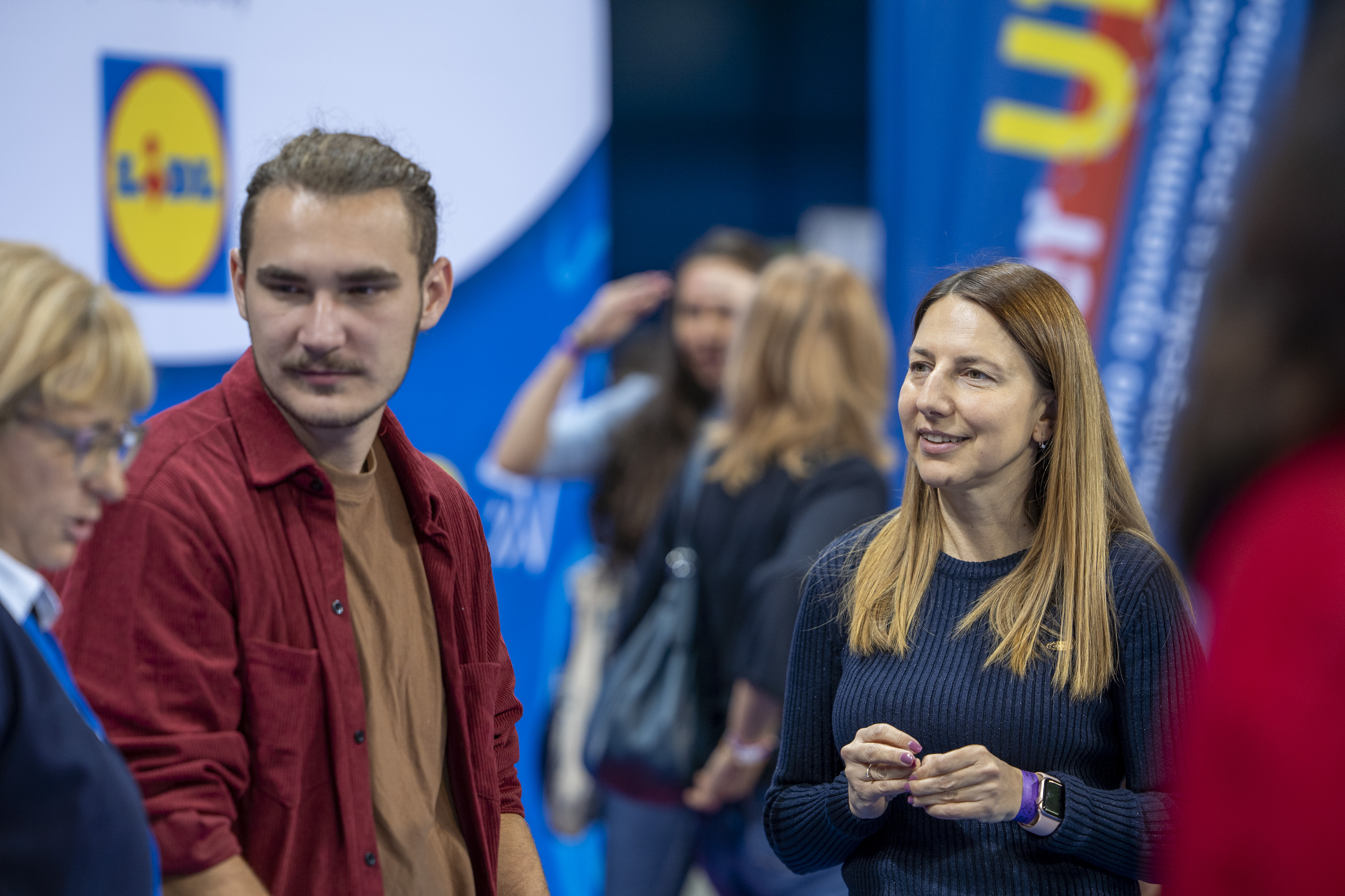Two women talk at a minimart booth.