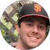 Young man smiling and wearing a black San Francisco Giants baseball cap. - Total Quality Lending Images
