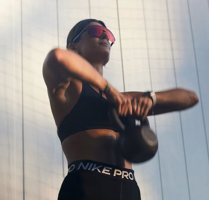 Frau mit Sonnenbrille trainiert mit einer Kettlebell.