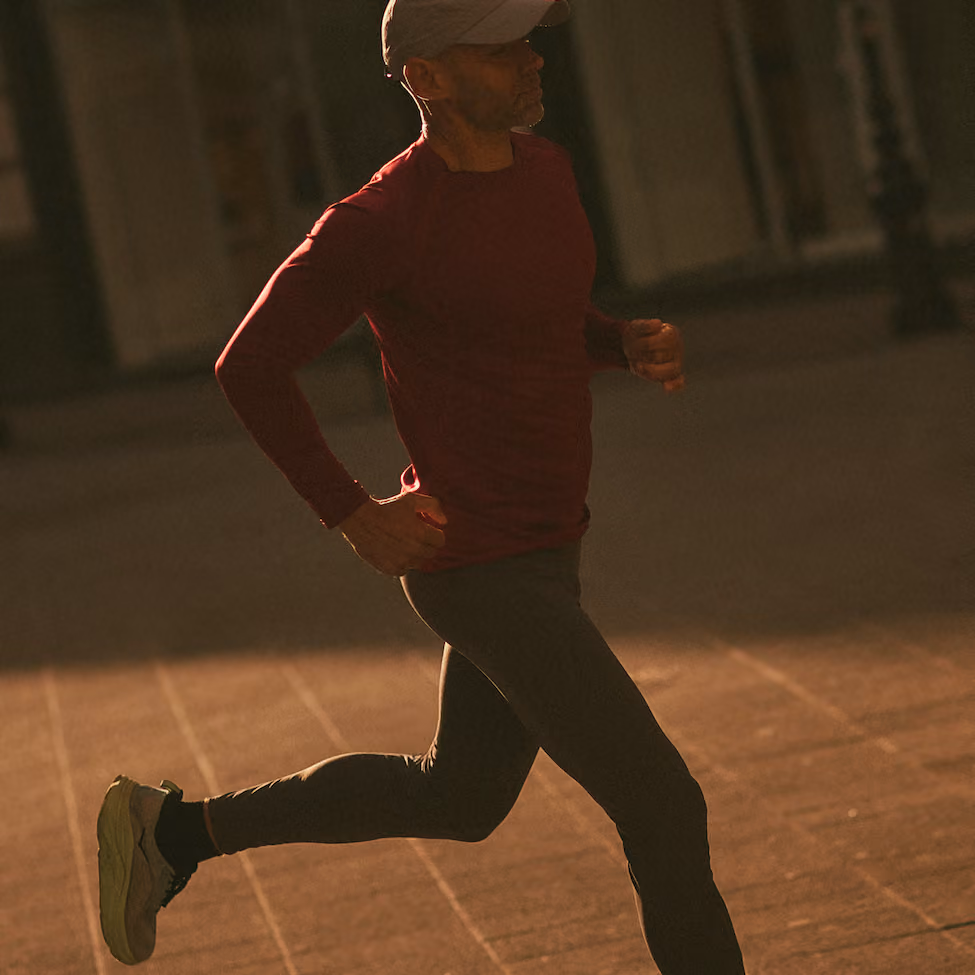 Mann joggt in rotem Oberteil und Cap, im Gegenlicht der Abendsonne.