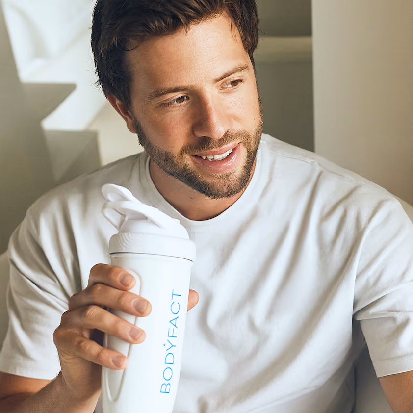 Lächelnder Mann hält eine BODYFACT Shaker-Flasche.