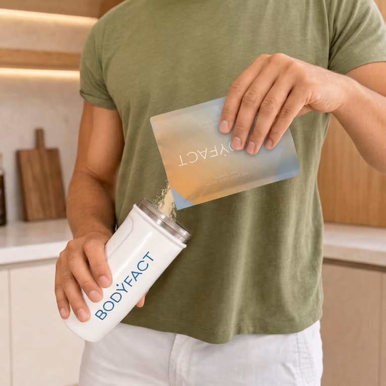 Man pouring BODYFACT powder from the pouch into a BODYFACT shaker bottle.