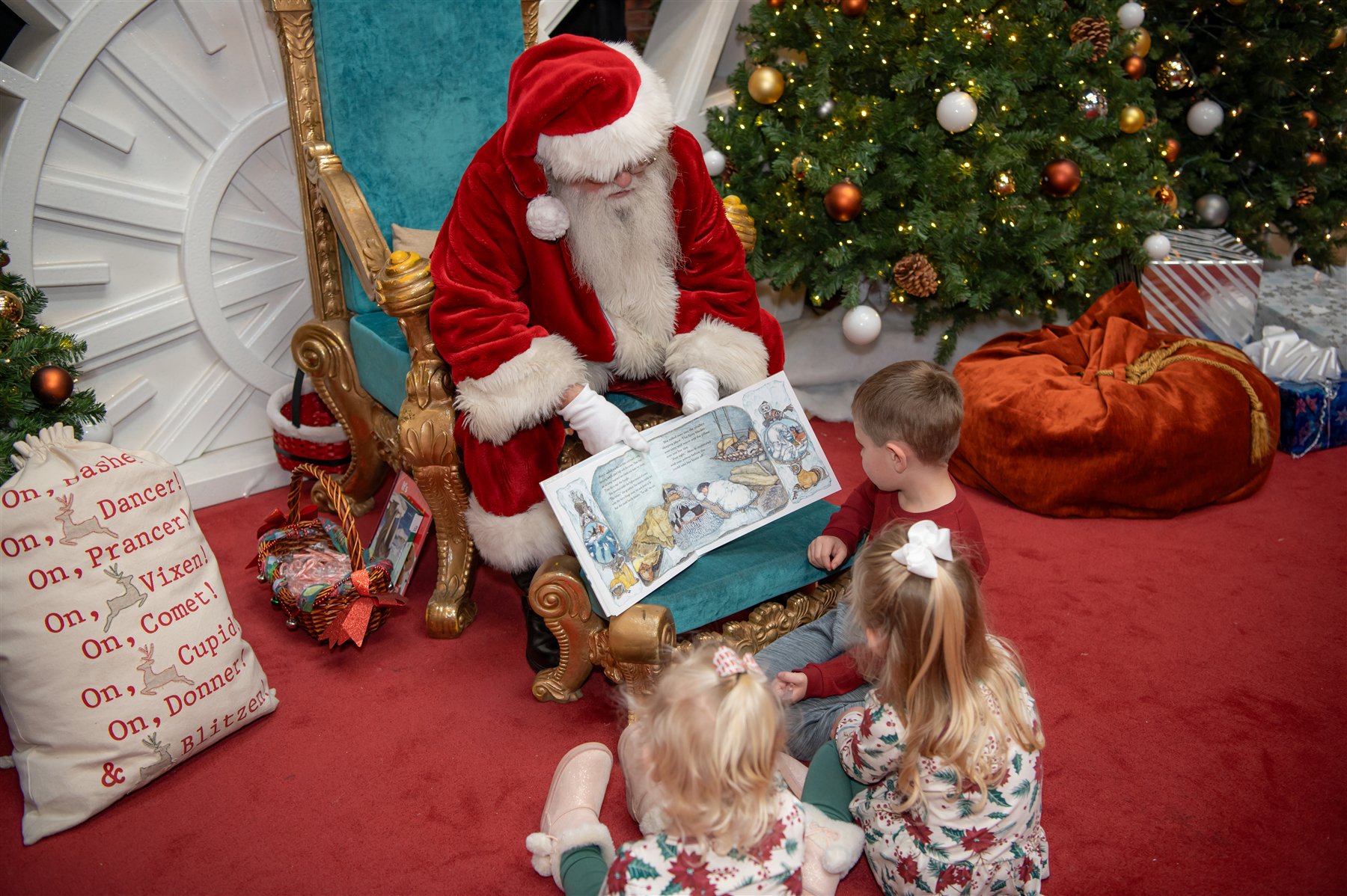 Santa Marty sharing a Christmas picture book with three children