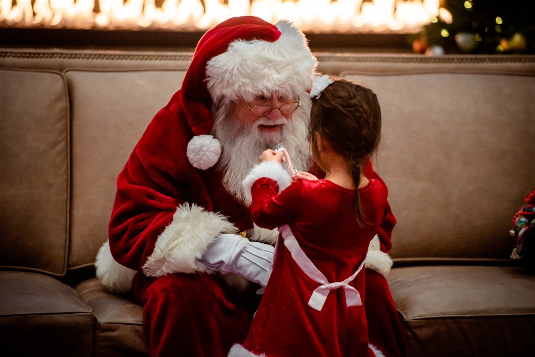 Santa Marty talking with a girl in a red dress holding a candy cane