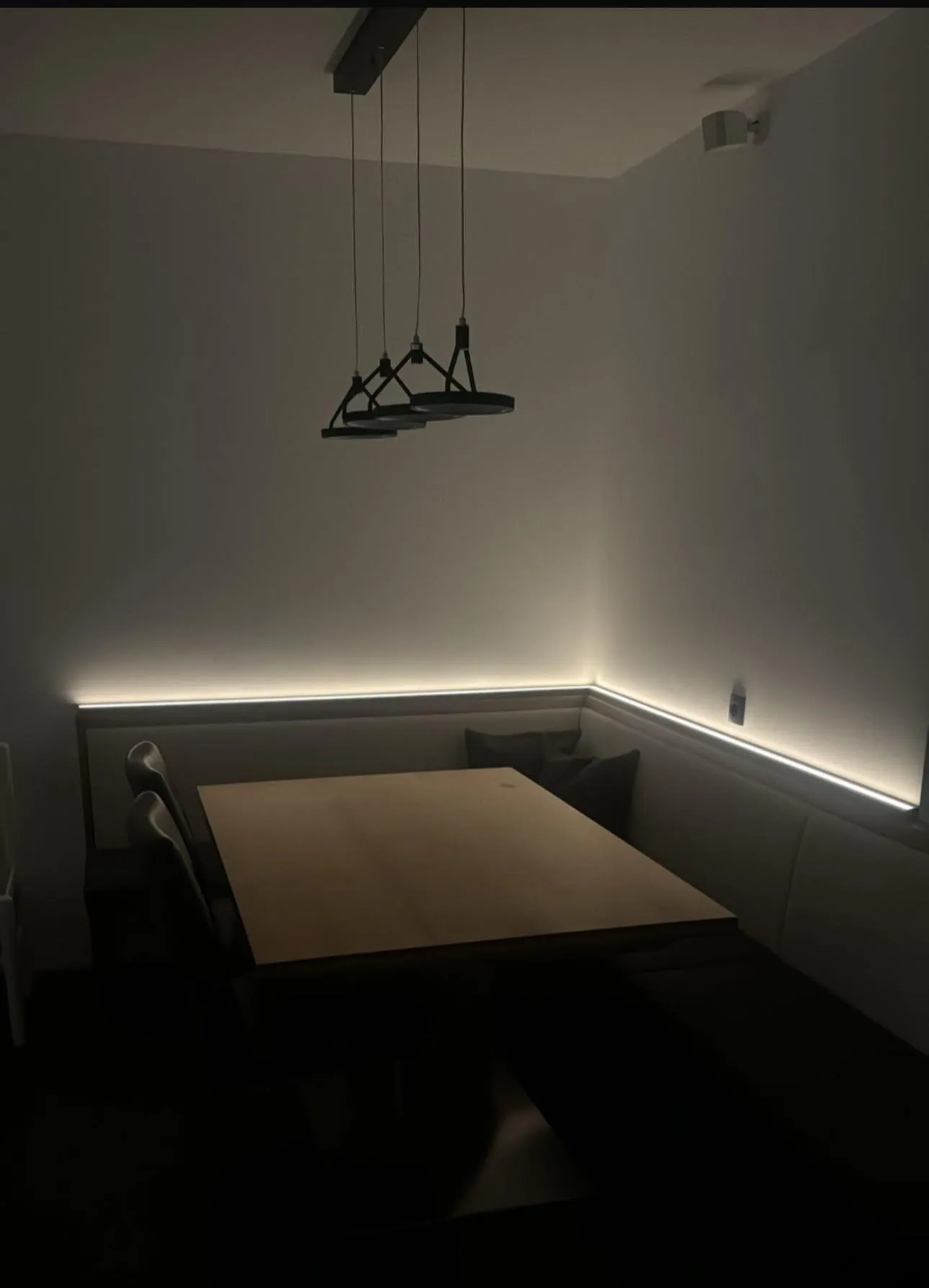 Zona pranzo con lampade a sospensione e illuminazione indiretta.