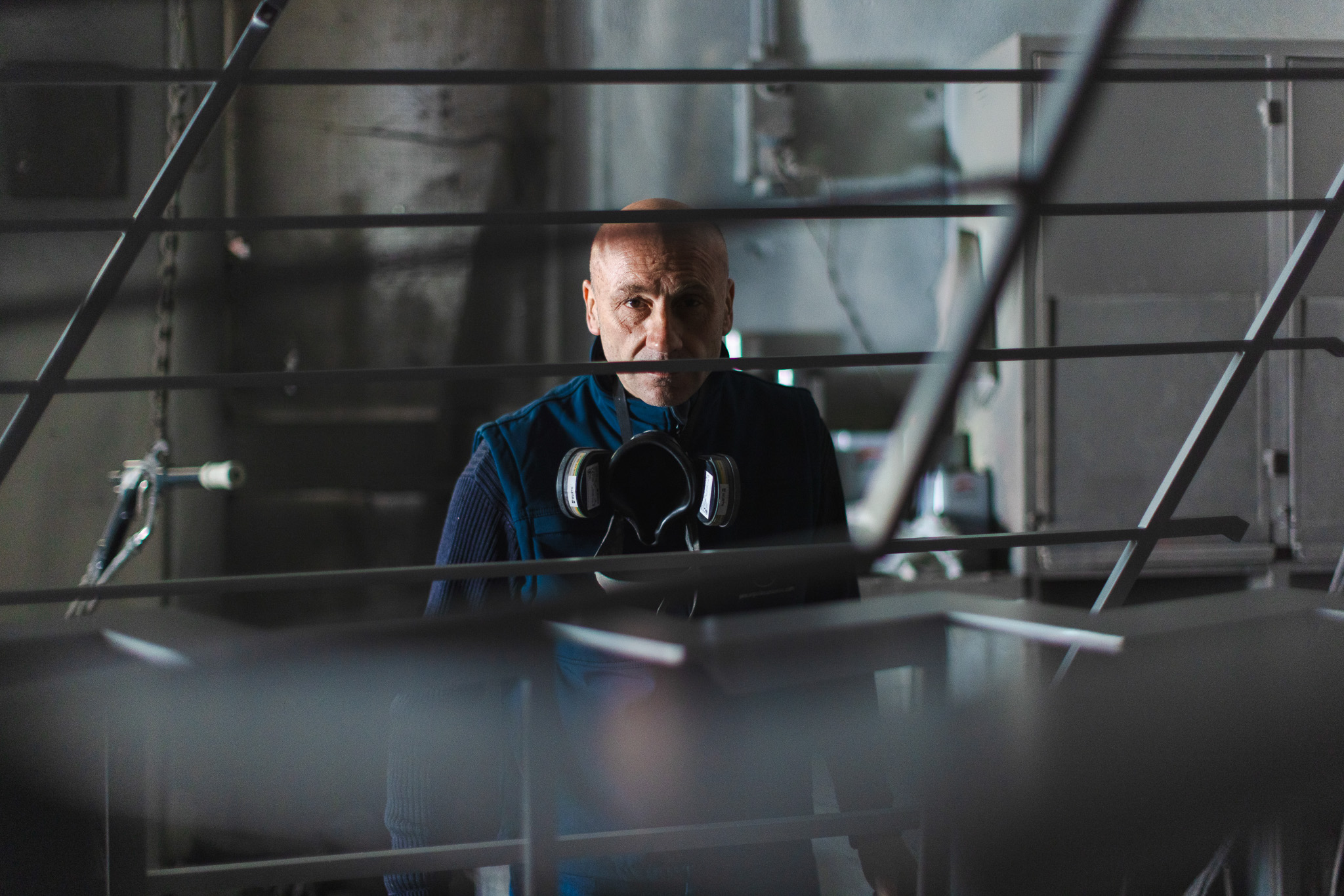 Uomo con maschera protettiva appesa al collo in ambiente industriale.