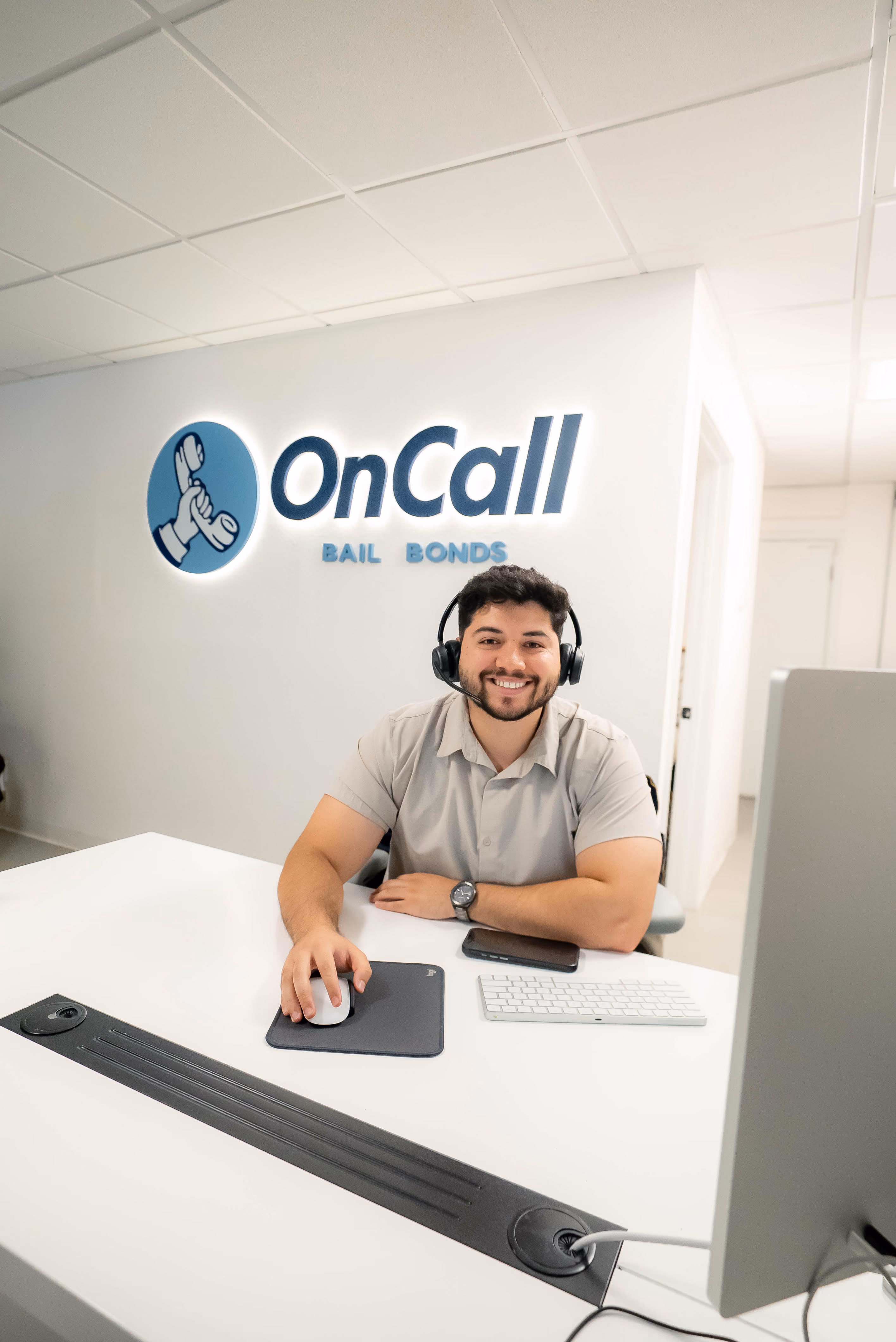 OnCall Bail Bonds agent at the front desk in front of the OnCall sign