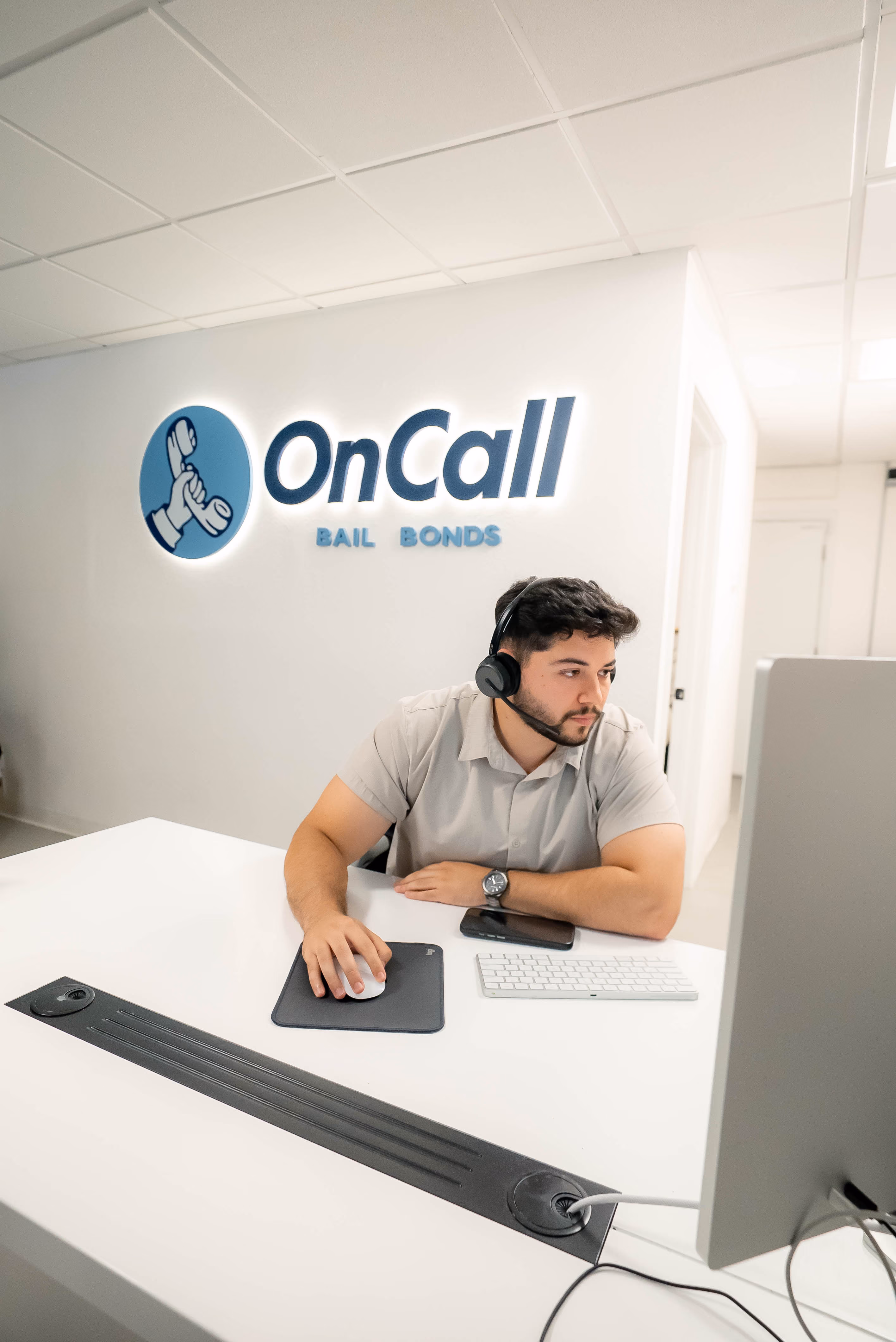OnCall Bail Bonds agent at a desk in front of the company logo