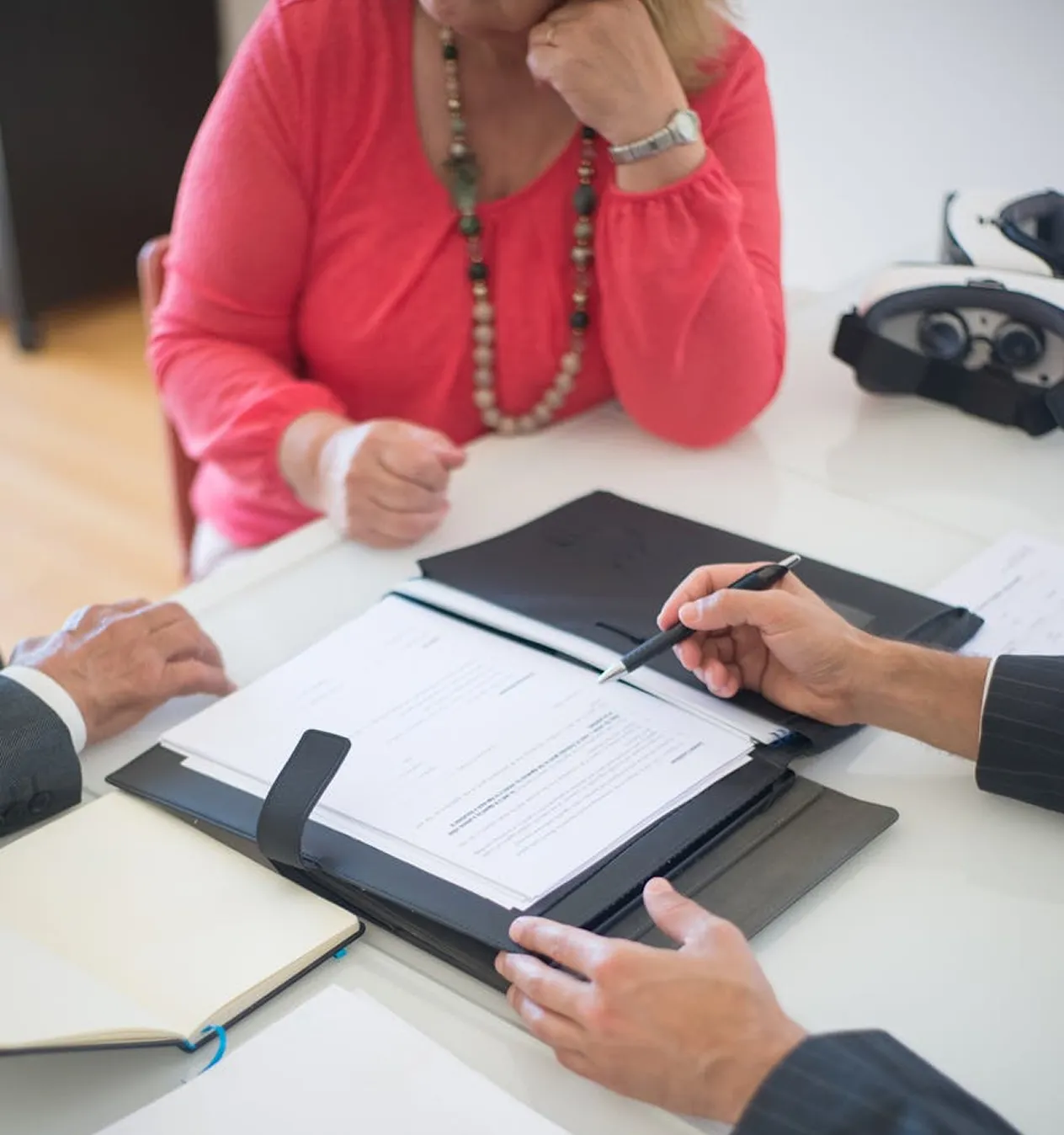 Advisor pointing a pen at a document in a folder while a client listens
