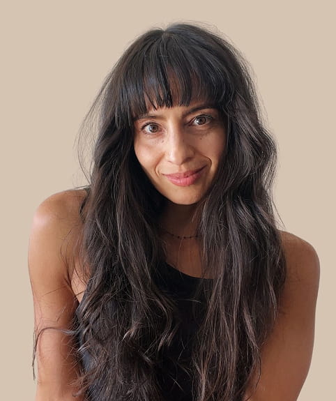 Elizabeth smiling against a plain beige background.