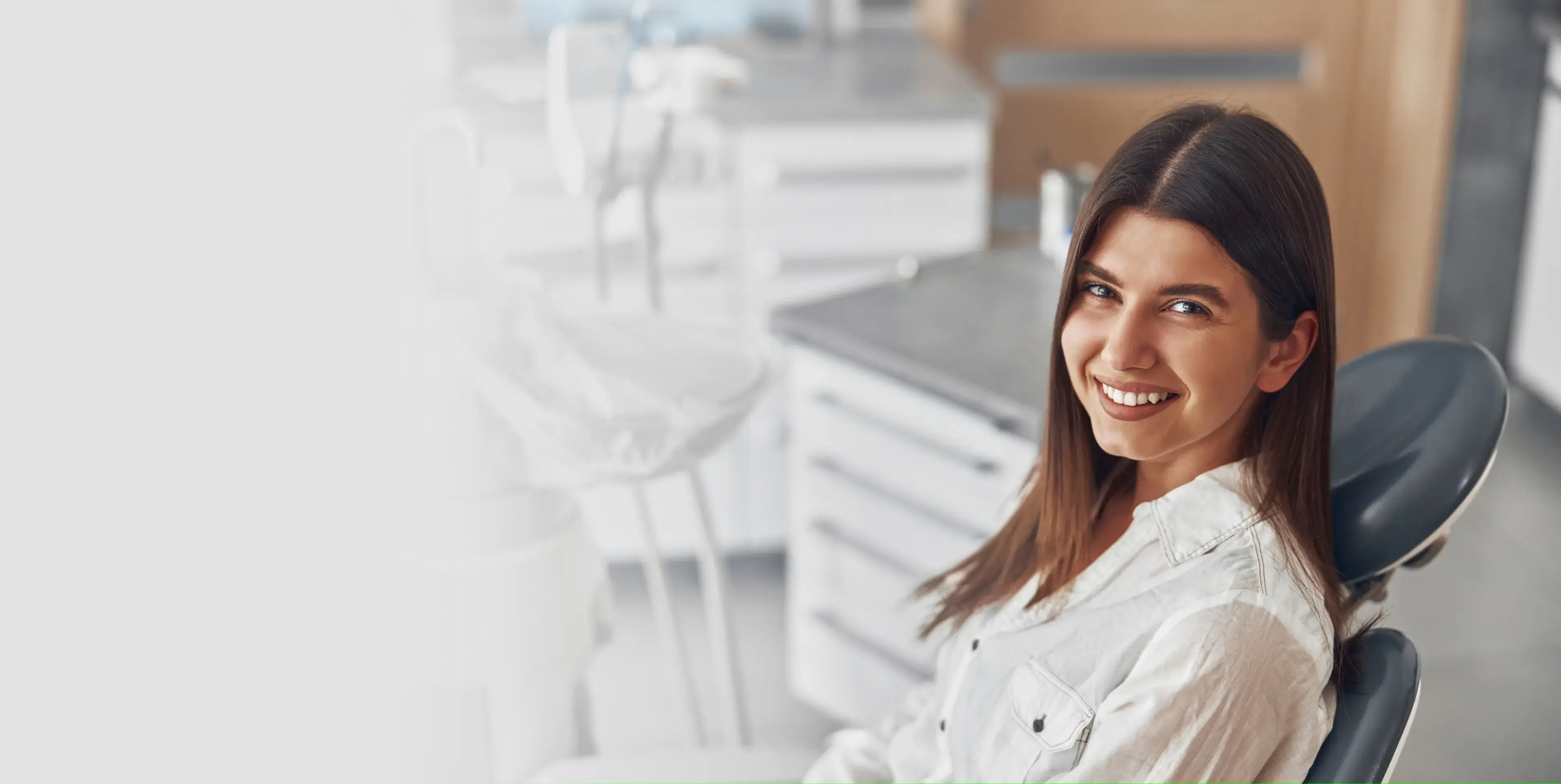 Smiling young woman sitting in a dental chair in a modern dental office.