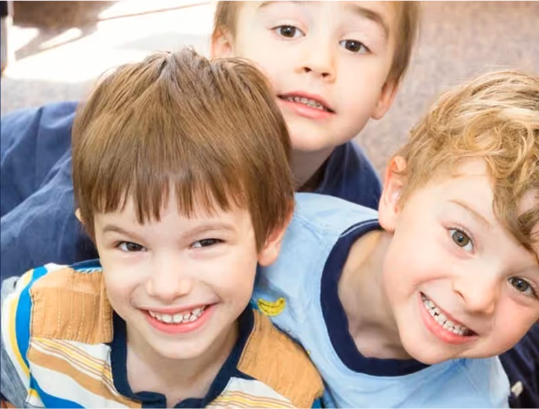 Three boys smiling and hugging each other