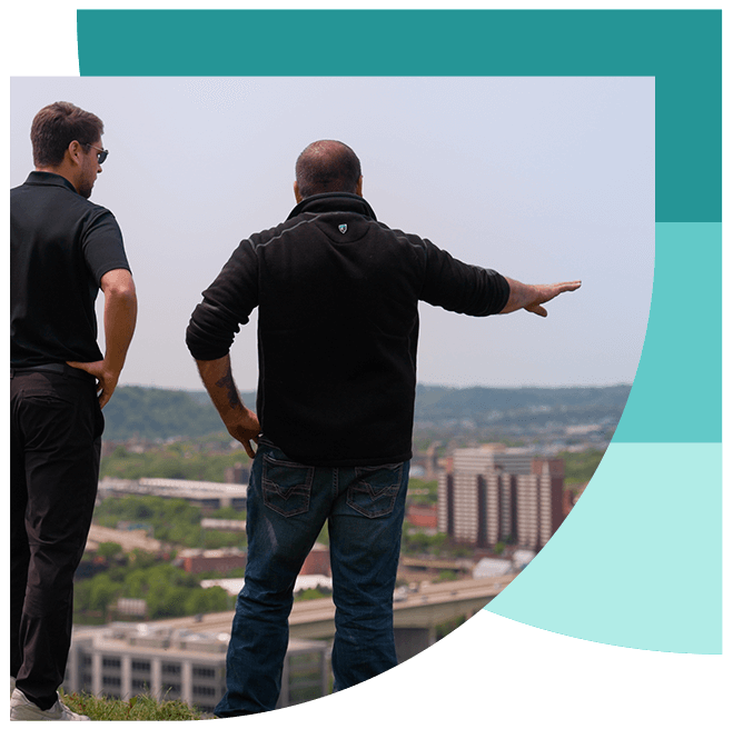 Upright employee and client overlooking downtown Pittsburgh discussing expansion plans