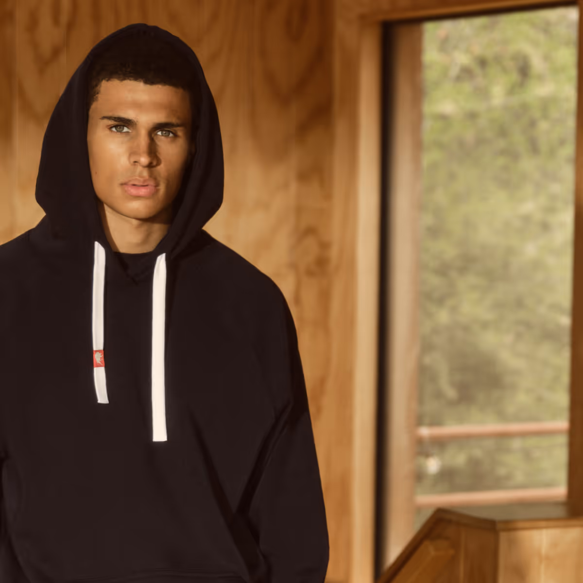 man in cabin-like setting wearing an black sportiqe olsen hoodie