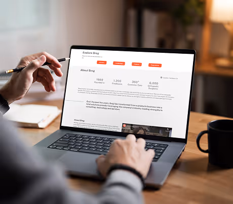 Laptop on a desk in an office setting. On the screen is a section of Breg's website.