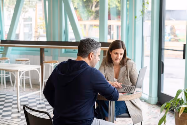 Businessman and businesswoman having a meeting in a cafe over a laptop