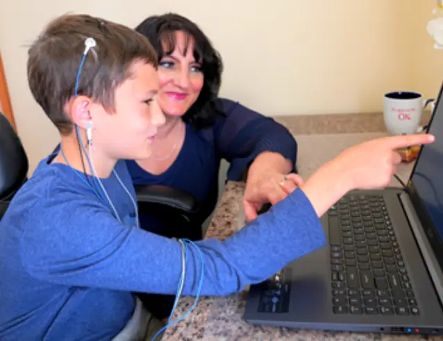 A woman and a boy looking at a computer screen.