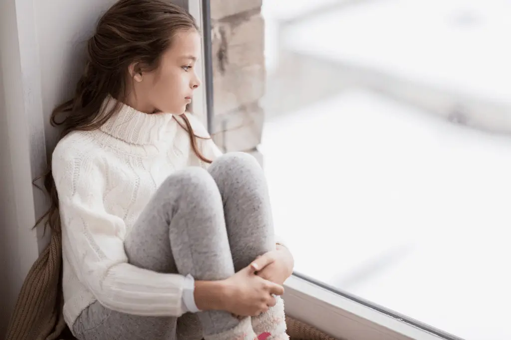 A young girl exhibiting mood and behavior while sitting on a window sill, as observed in the Clinical Guide.