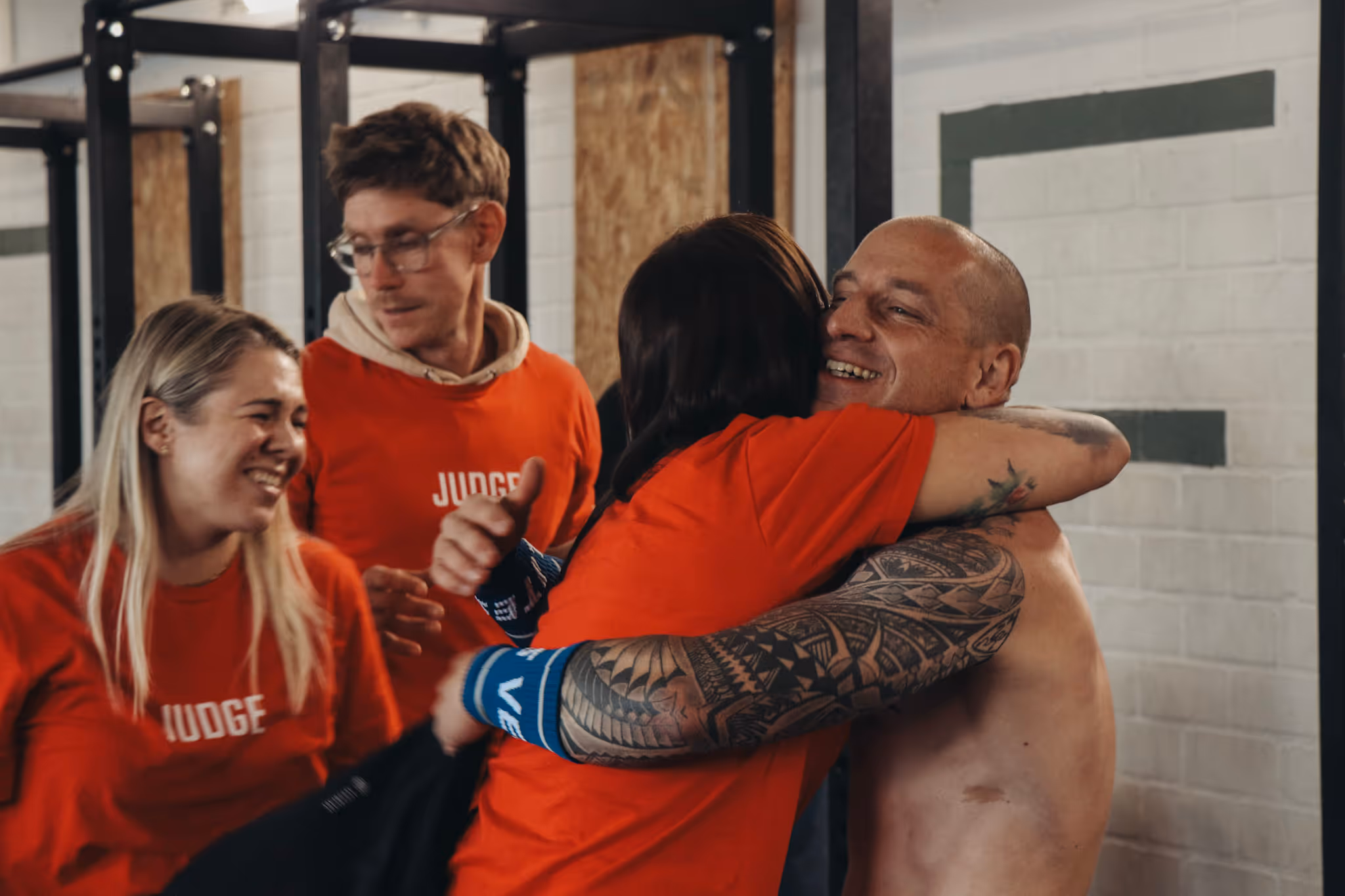 Zwei Personen umarmen sich herzlich in einem Trainingsraum.