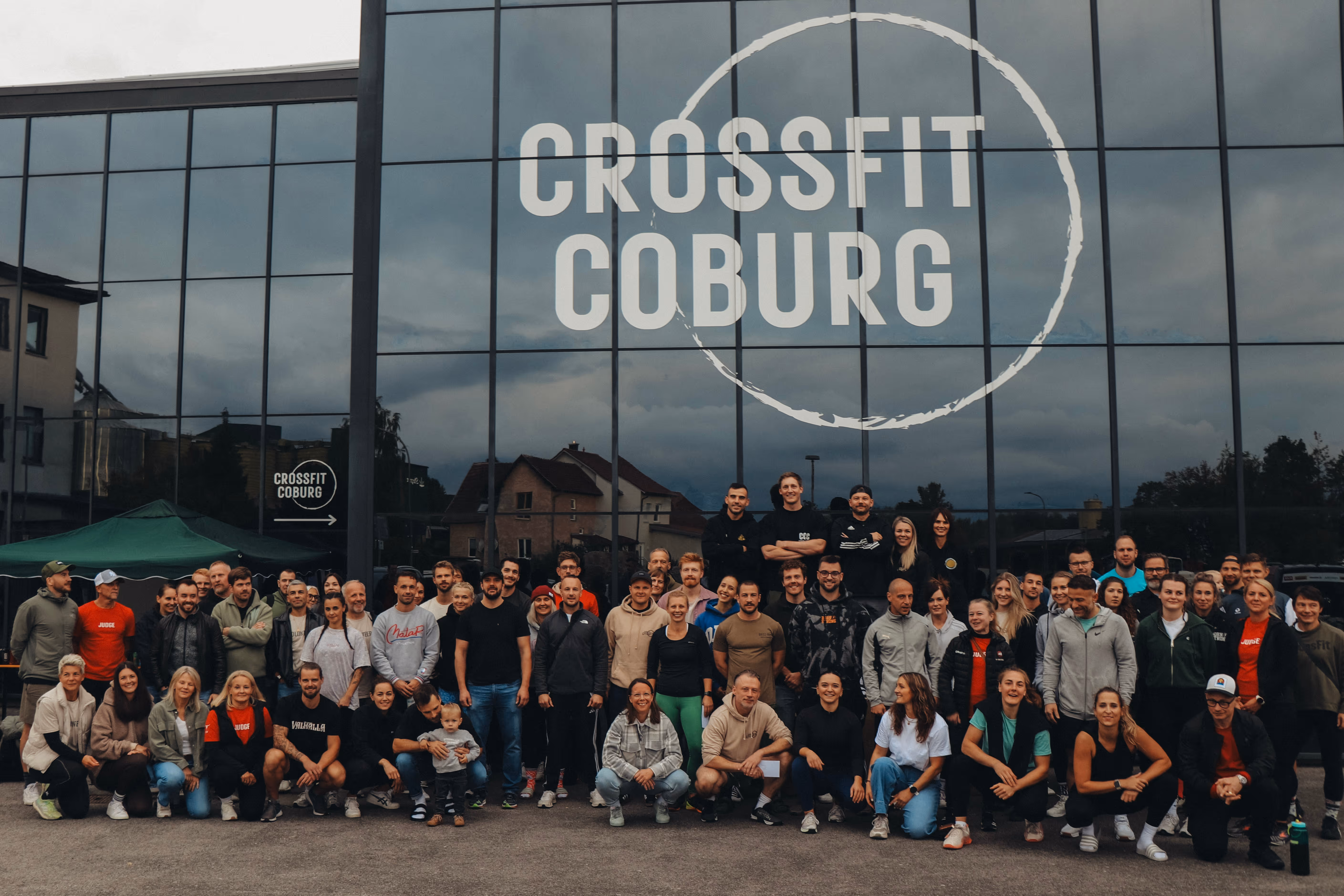 Große Gruppe von Menschen posiert vor einem Glasgebäude mit der Aufschrift Crossfit Coburg.