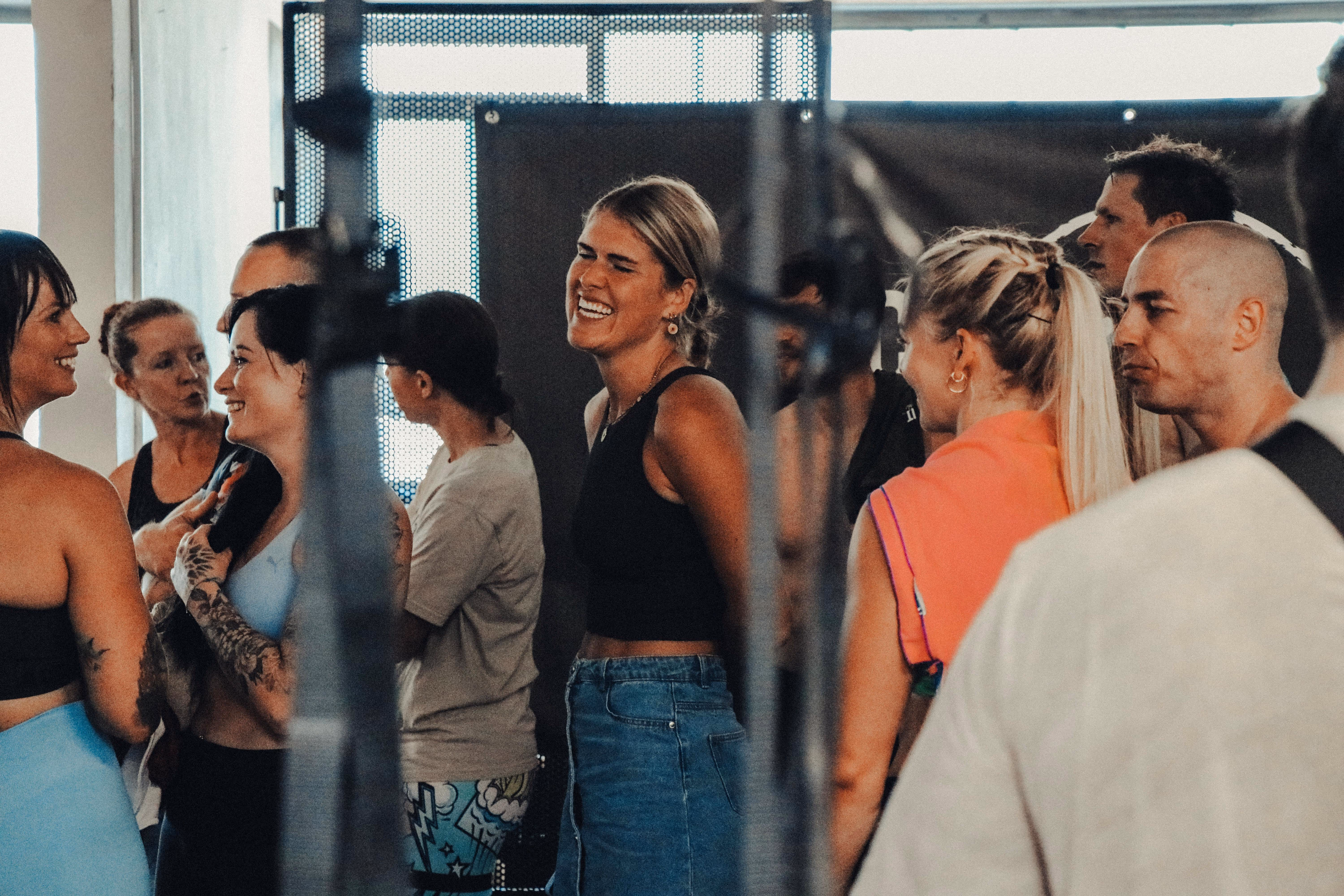 Gruppe von Menschen in entspannter Atmosphäre, einige lachen und unterhalten sich.