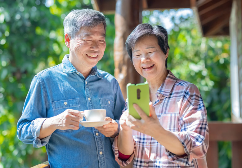 Senior couple looking at phone and smiling.
