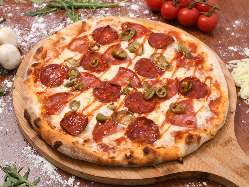 Pepperoni pizza on a wooden round serving board.