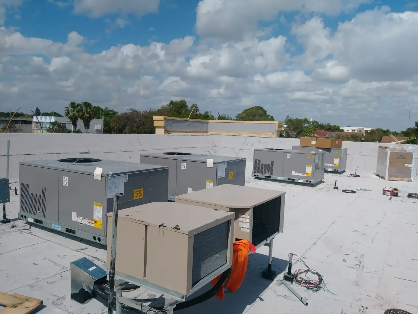 Commercial HVAC units on a white roof under cloudy blue sky