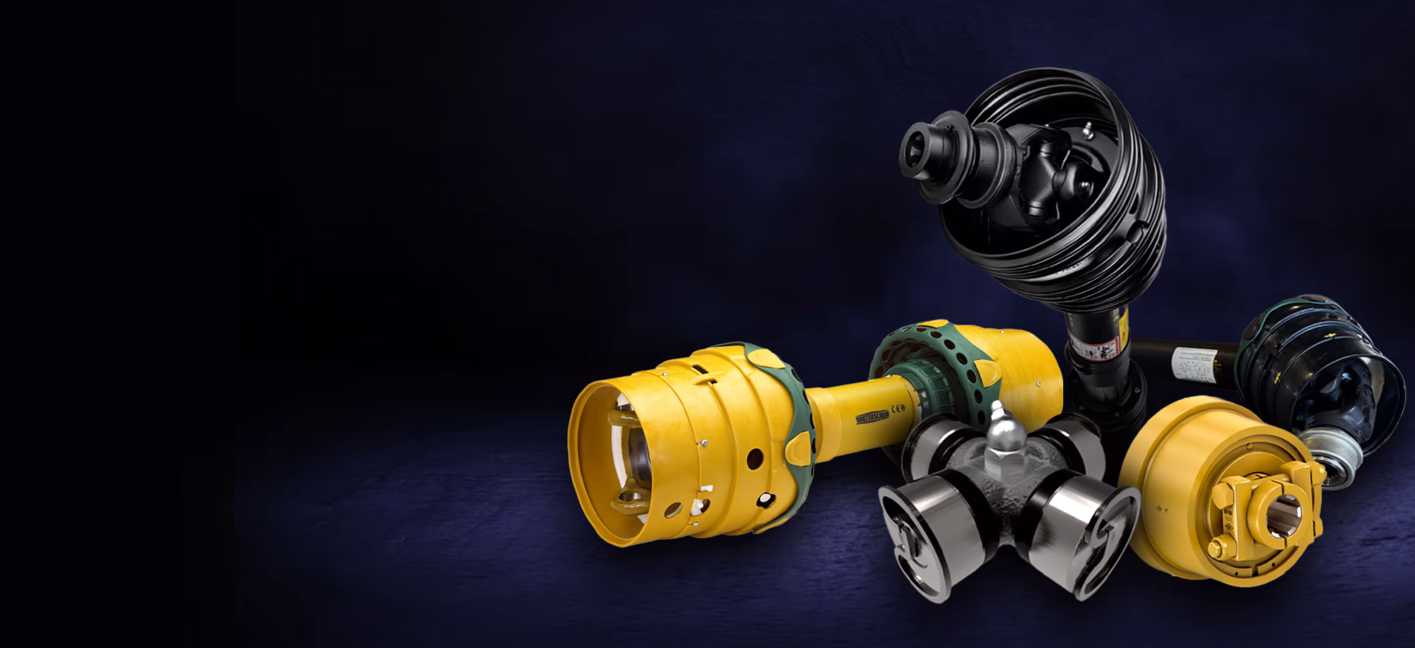 Various heavy-duty yellow and black mechanical driveshaft components on a dark blue background.