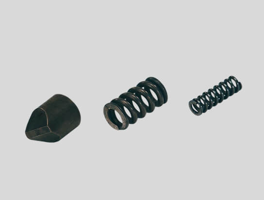 Three mechanical parts including a pointed metal piece and two coiled springs of different sizes on a gray background.