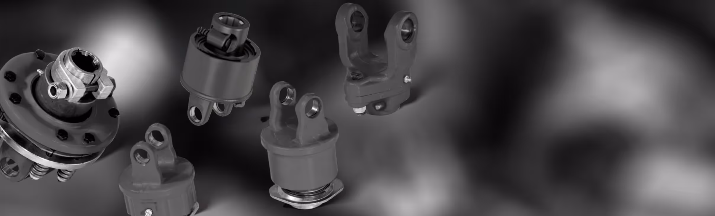 Five different black automotive suspension or drivetrain components against a dark, blurred background.