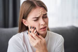 Girl holding her jaw as she experiences severe tooth pain