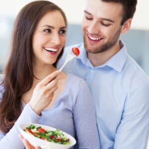 Couple eating a vegetable salad in the living room