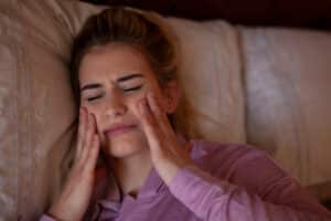 Stress woman clutching jaw in pain from TMJ disorder