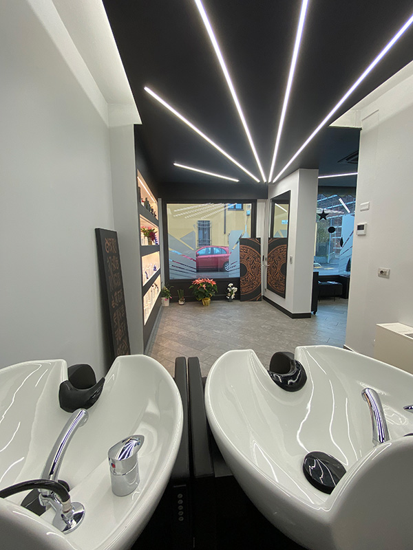 Modern salon interior with two white hair washing basins and linear ceiling lights.