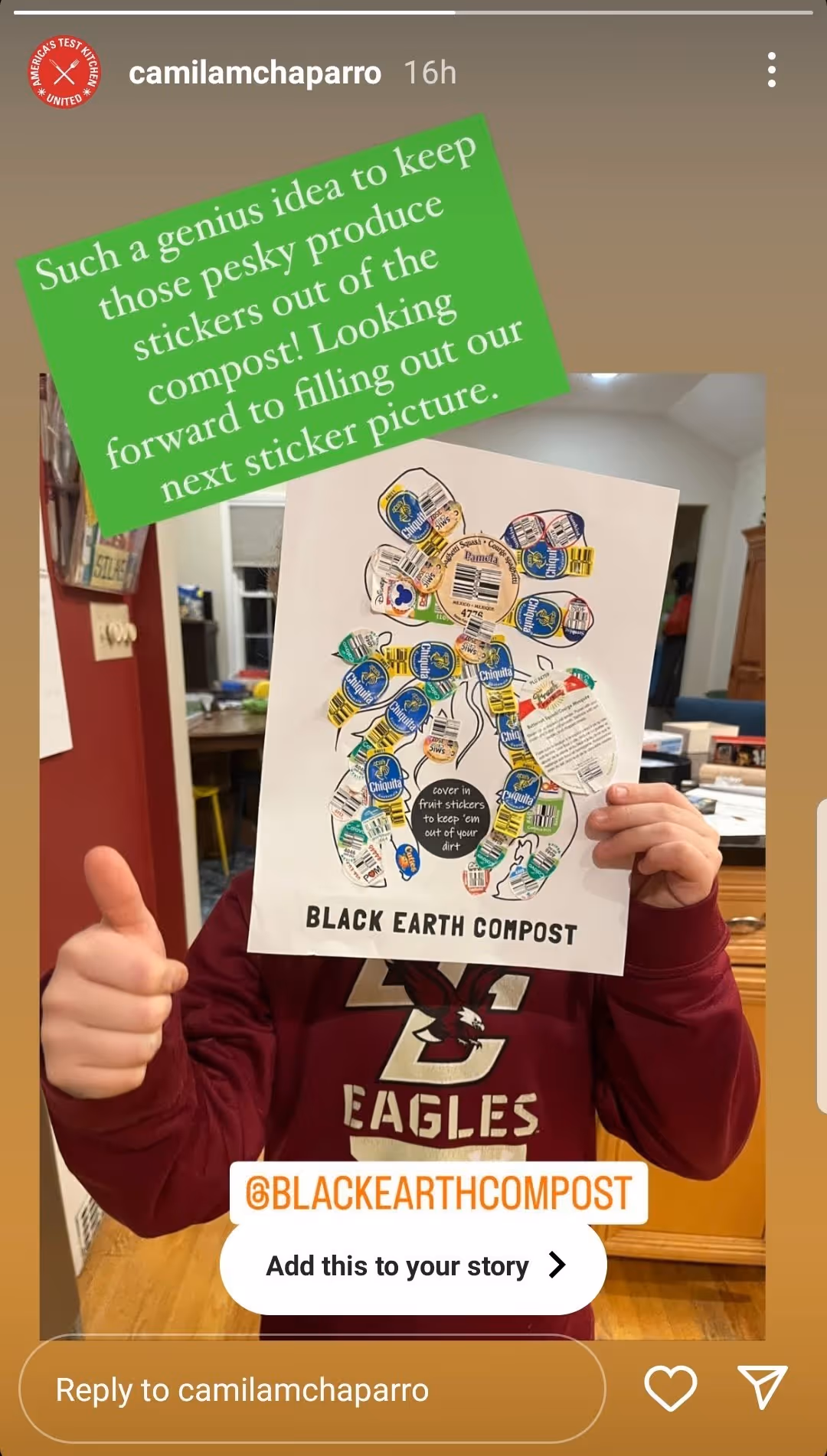Person in a maroon Eagles sweatshirt holds a paper with various fruit stickers arranged in a figure, promoting Black Earth Compost with a thumbs up gesture.