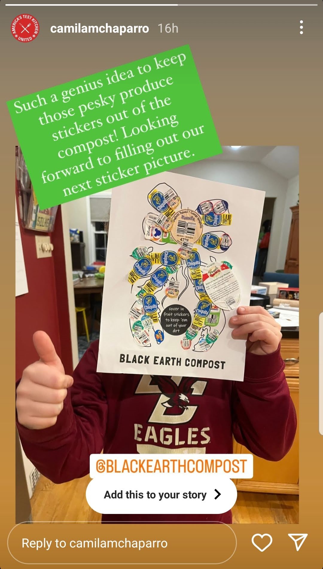 Person in a maroon Eagles sweatshirt holds a paper with various fruit stickers arranged in a figure, promoting Black Earth Compost with a thumbs up gesture.