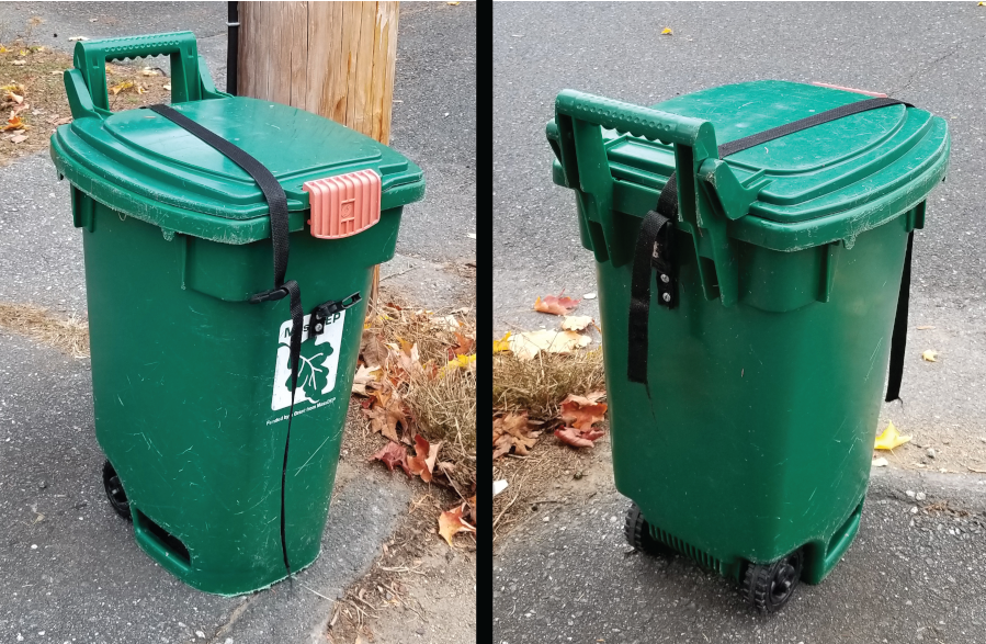 Green outdoor wheeled trash bin with a black strap securing the lid, shown from two angles on a paved surface near a wooden post.