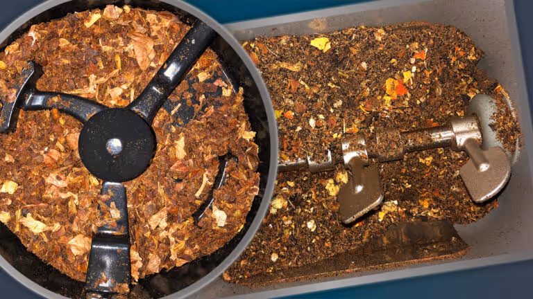 Close-up of a composting machine's interior showing decomposing organic material and the mixing blades.