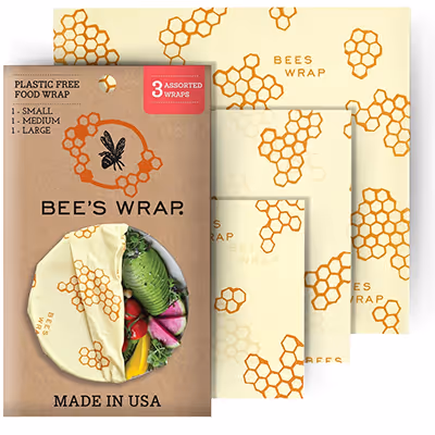 Three assorted sizes of Bee’s Wrap plastic-free food wraps with honeycomb pattern and packaging showing a wrap covering fresh vegetables.