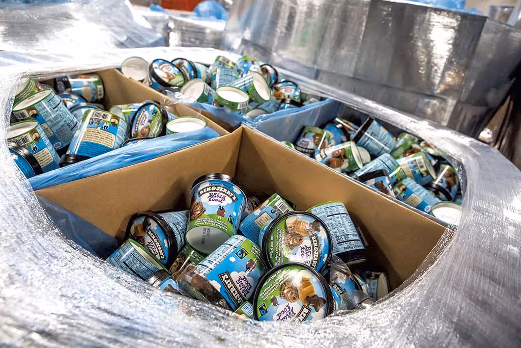 Cardboard boxes filled with Ben & Jerry's ice cream pints wrapped in plastic on a pallet.