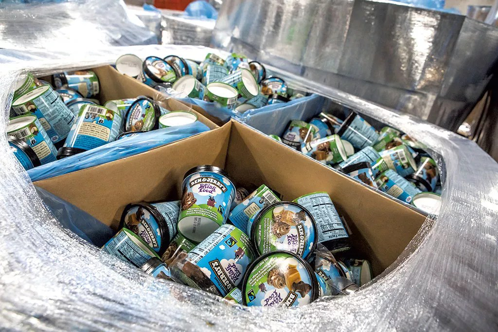 Cardboard boxes filled with Ben & Jerry's ice cream pints wrapped in plastic on a pallet.
