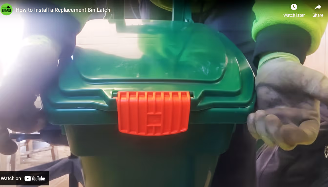Person wearing gloves handling a green bin with a bright red replacement latch on the lid.