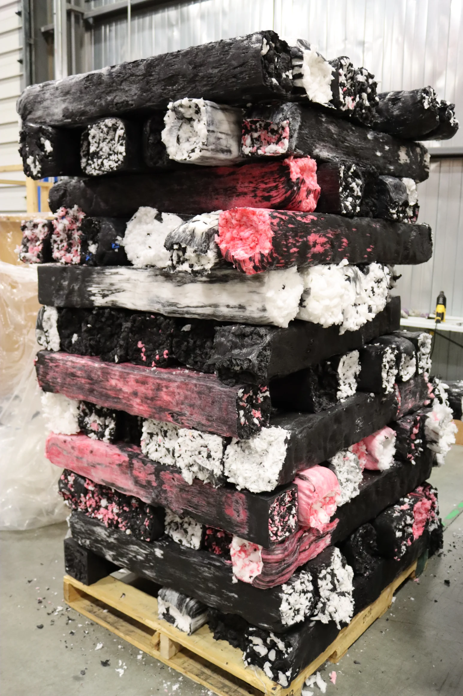 Red packing tape roll resting on white packing peanuts inside a cardboard box.