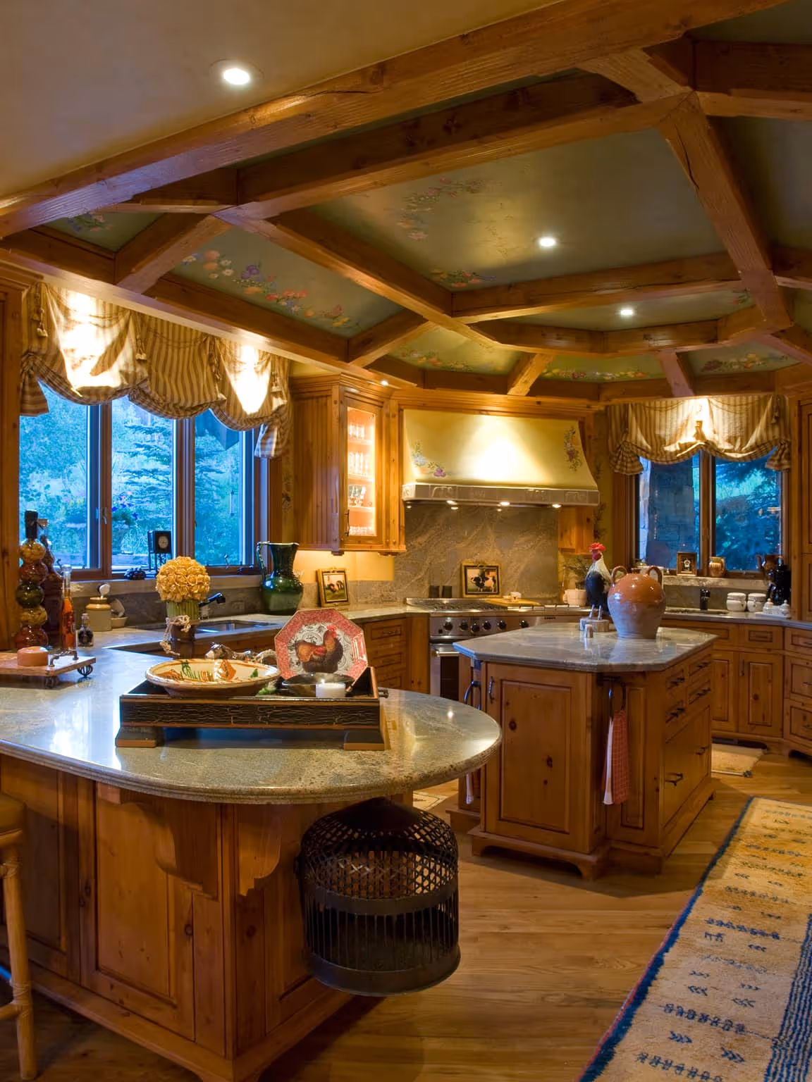 Rustic kitchen with wood cabinetry, green floral ceiling beams, marble countertops, and decorative rooster-themed items.